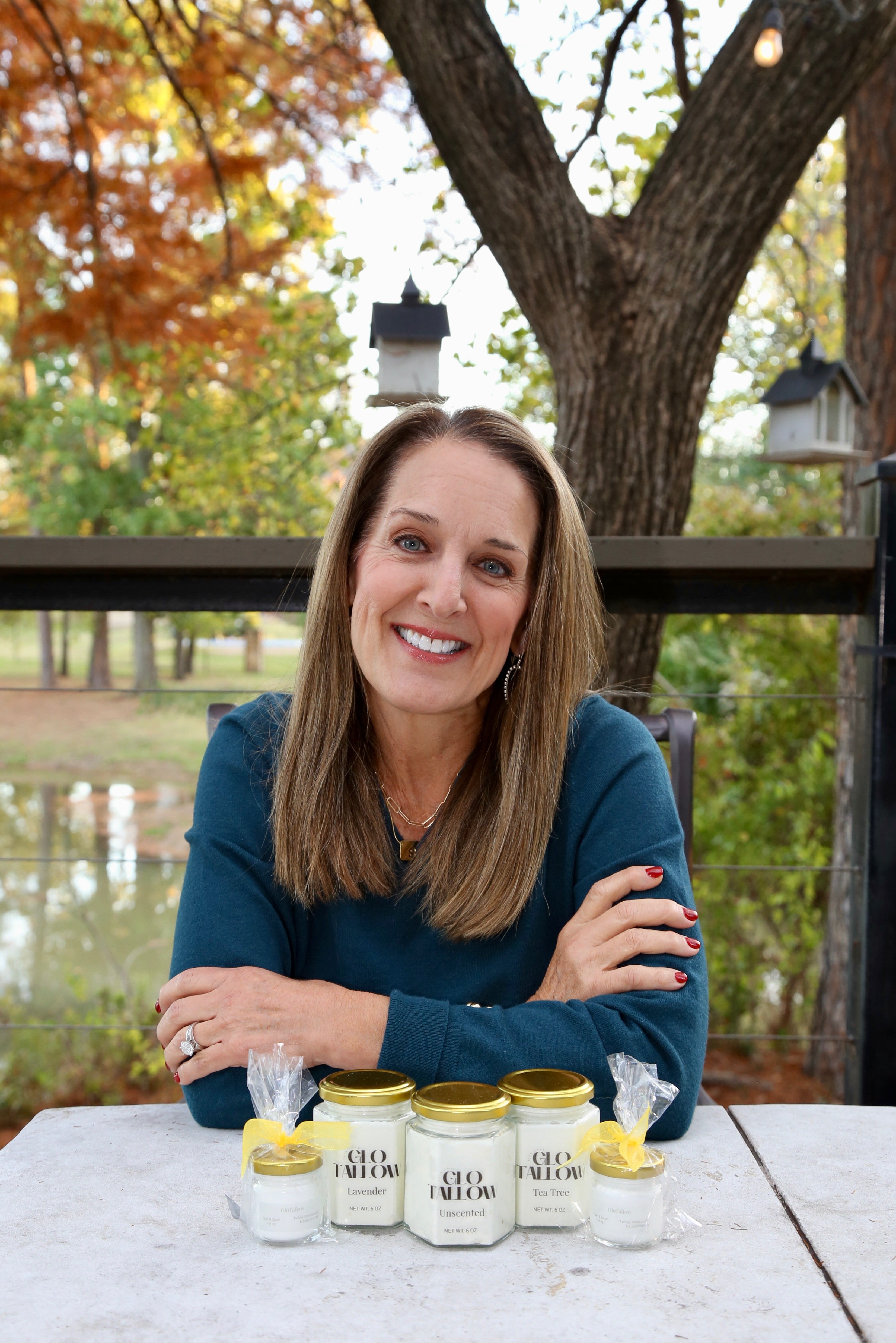 Ladie sitting at a Table with jars of Tallow in an outdoor setting