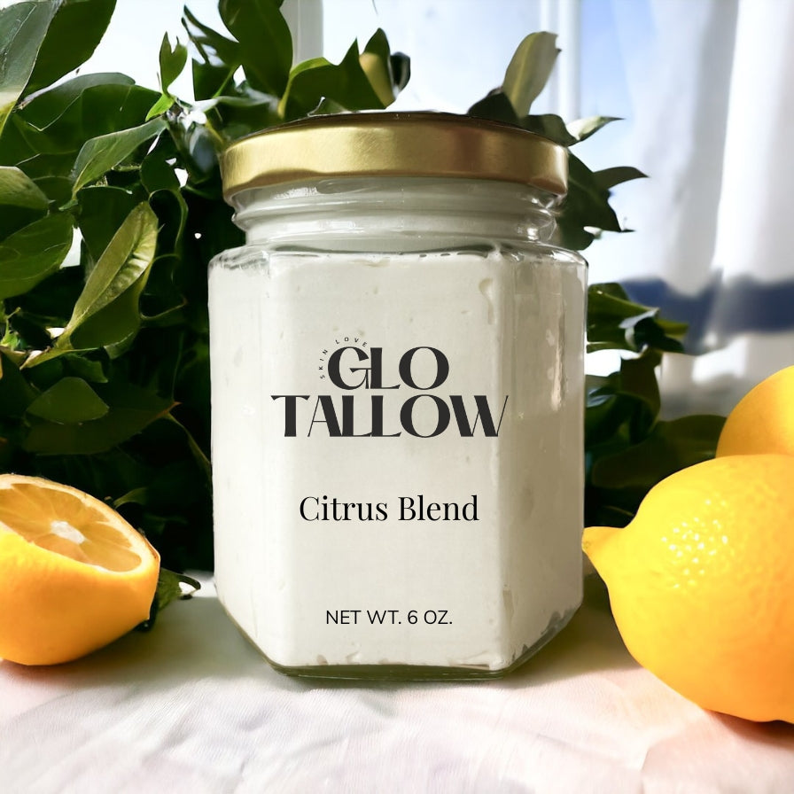 Glo Tallow 6oz jar of Citrus Blend Tallow sitting on a white counter with citrus fruit laying next to it