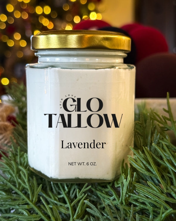 Glo Tallow lavender Tallow Balm in a jar with a gold lid on a green leafy background.