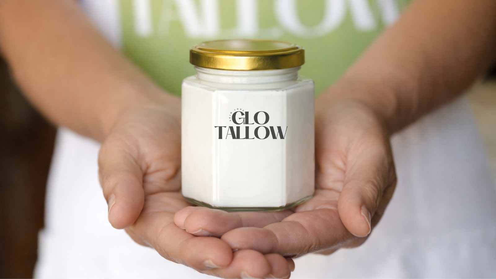 Jar of 'Glo Tallow' held in hands with a blurred background