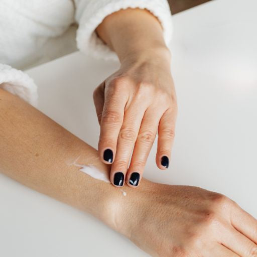 Person applying cream to their arm with a white background